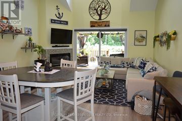 Ramara (Brechin) townhouse for rent - A living room with a fireplace and a dining table with chairs.