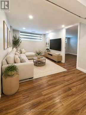 Burlington (Appleby) apartment for rent - A living room with a white couch, a wooden floor, and a flat screen TV.