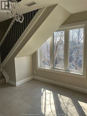 Windsor apartment for rent - A sunny room with a staircase and a window showing trees outside.