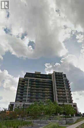 Toronto (York University Heights) condo for rent - A large, modern building with many windows is surrounded by greenery.