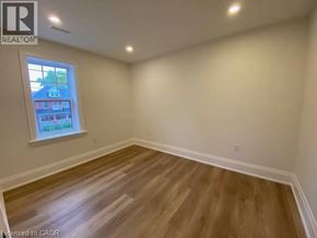 Stratford apartment for rent - A room with wooden flooring and a window showing a view of a house.