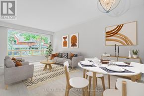 Toronto (East End-Danforth) apartment for rent - A modern dining room with a white table and chairs, a grey sofa, and a large window with a view of a house.