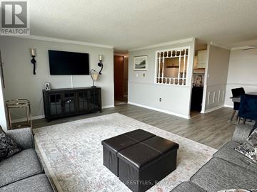 London South (South J) condo for rent - A living room with a grey sofa, a black coffee table, and a television mounted on the wall.