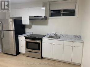 Toronto (Englemount-Lawrence) apartment for rent - A kitchen with white cabinets and a black fridge.
