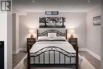 Hamilton (Waterdown) apartment for rent - A bedroom with a large bed and a painting of a tree on the wall.