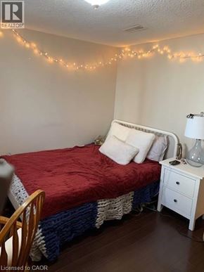 Waterloo apartment for rent - A bedroom with a bed, nightstand, and lights on the wall.