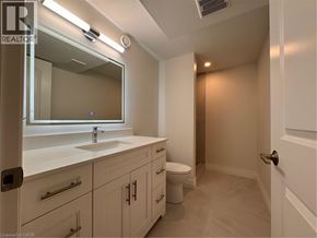 Kitchener apartment for rent - A bathroom with a sink, mirror, and toilet.