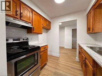 Kitchener apartment for rent - A kitchen with wooden cabinets and a stove top oven.