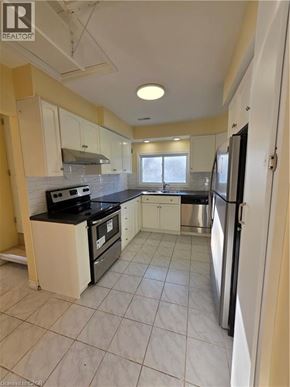 Hamilton apartment for rent - A kitchen with white cabinets and black appliances.