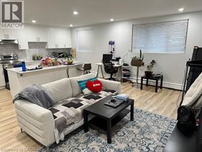 Kitchener apartment for rent - A living room with a couch, coffee table, and a kitchen area in the background.