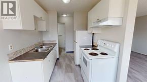 Grande Prairie apartment for rent - A white kitchen with a stove, sink, and cabinets.