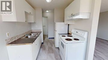 Grande Prairie apartment for rent - A white kitchen with a stove, sink, and cabinets.