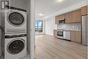 Toronto (Rouge) condo for rent - A realtor photo of a clean, empty apartment with a washer and dryer in the foreground.