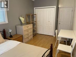 Burnaby apartment for rent - A bedroom with a bed, dresser, and chair.
