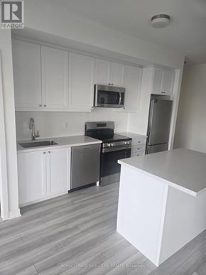 Clarington (Bowmanville) condo for rent - A kitchen with white cabinets and a grey floor.