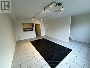 Mississauga (Cooksville) apartment for rent - A spacious room with a black rug in the middle and white walls.
