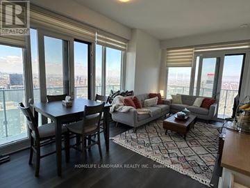 Mississauga (City Centre) condo for rent - A living room with a dining table and a couch with a view of the city.