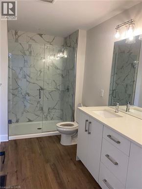 Komoka townhouse for rent - A bathroom with a marble patterned shower and white toilet.