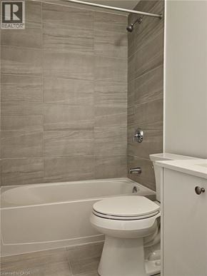 Kitchener townhouse for rent - A white toilet in a bathroom with a tiled wall.