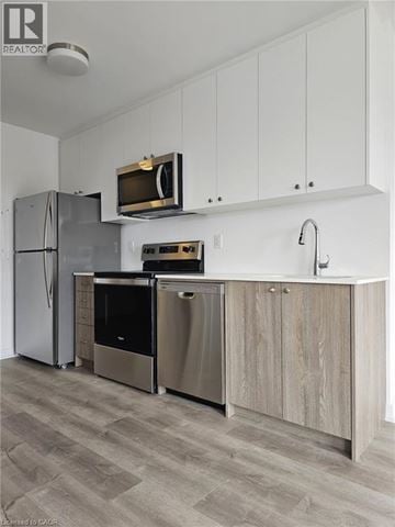 Kitchener townhouse for rent - A modern kitchen with a refrigerator, oven, and microwave.
