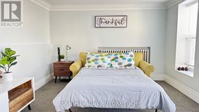 Niagara Falls (Dorchester) apartment for rent - A bedroom with a bed, a yellow chair, and a plant.