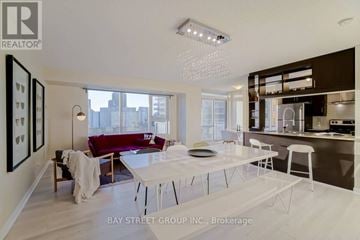 Toronto (Bendale) condo for rent - A modern living room with a dining table and chairs, a sofa, and a kitchen area in the background.