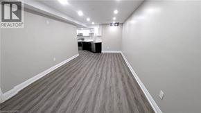 Hamilton apartment for rent - A spacious room with wooden flooring and white walls, likely a living space or office.