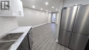 Hamilton apartment for rent - A stainless steel refrigerator is in a kitchen with a sink and wooden flooring.
