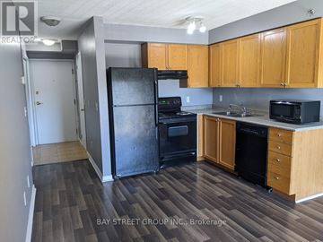 Toronto (Clairlea-Birchmount) condo for rent - A kitchen with wooden cabinets and a black refrigerator.