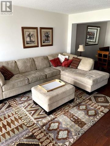 Ottawa townhouse for rent - A living room with a beige couch, a matching ottoman, and a rug with a geometric pattern.
