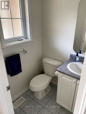 Ottawa townhouse for rent - A white toilet sits next to a sink in a small bathroom.
