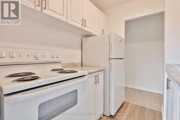 Oshawa (Lakeview) condo for rent - A white stove and refrigerator in a kitchen with white cabinets.
