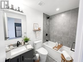 Burlington (Alton) condo for rent - A bathroom with a white toilet, sink, and bathtub.