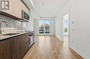 Toronto (South Riverdale) condo for rent - A modern kitchen with wooden cabinets and a stainless steel oven.