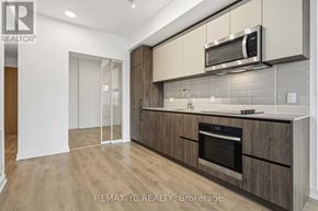 Toronto (South Riverdale) condo for rent - A modern kitchen with wooden cabinets and a stainless steel oven.