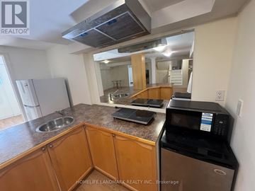 Richmond Hill (Rouge Woods) apartment for rent - A kitchen with wooden cabinets and a black microwave.