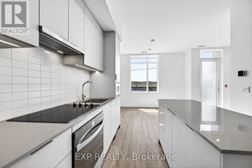 Oakville (Jm Joshua Meadows) condo for rent - A modern kitchen with white cabinets and black countertops.