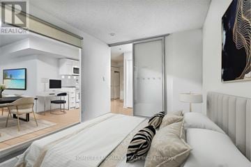 Toronto (Waterfront Communities) condo for rent - A bedroom with a large bed and a television in the living room.