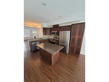 Langley townhouse for rent - A kitchen with brown cabinets and a granite countertop.