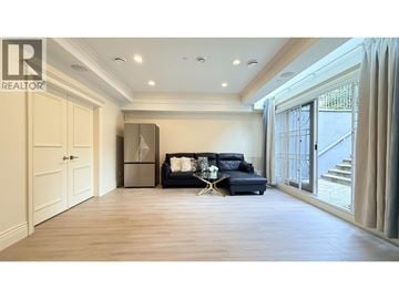 Vancouver apartment for rent - A spacious living room with a black sofa and a wooden floor.