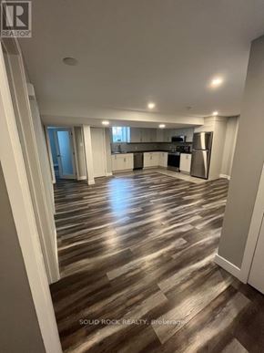 Russell apartment for rent - A spacious room with wood flooring and a kitchen area in the background.