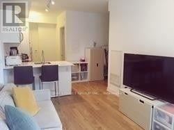 Toronto (Bay Street Corridor) condo for rent - A living room with a white couch and a television.