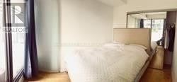 Toronto (Bay Street Corridor) condo for rent - A bedroom with a bed, a mirror, and a wardrobe.