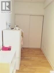 Toronto (Bay Street Corridor) condo for rent - A white refrigerator sits in a kitchen with a white wall and wooden floor.