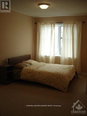 Ottawa townhouse for rent - A bedroom with a bed, nightstand, and window with curtains.
