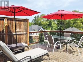 Wasaga Beach apartment for rent - A deck with chairs and umbrellas is surrounded by a wooden fence.