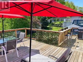 Wasaga Beach apartment for rent - A red umbrella is on a wooden deck with a table and chairs.