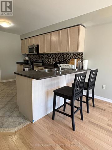 Wasaga Beach apartment for rent - A kitchen with a black counter top and two black chairs.