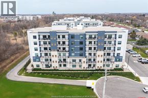 Windsor condo for rent - A large apartment building with a parking lot in front.