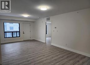 Windsor condo for rent - A realtor logo is on the wall in a room with a window and a door.